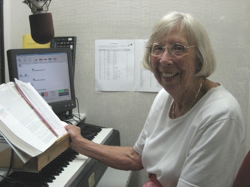 Learning Ally studio volunteer sitting at piano keyboard in a recording booth.