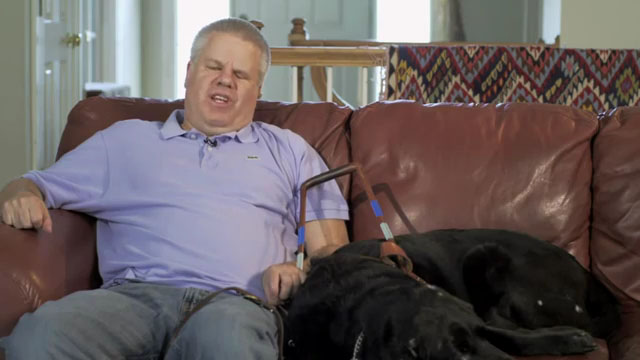 Blind author Peter Altschul and guide dog sitting on sofa
