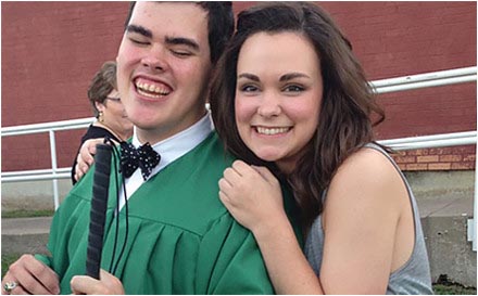 Student who is blind in graduation cap and gown with sister